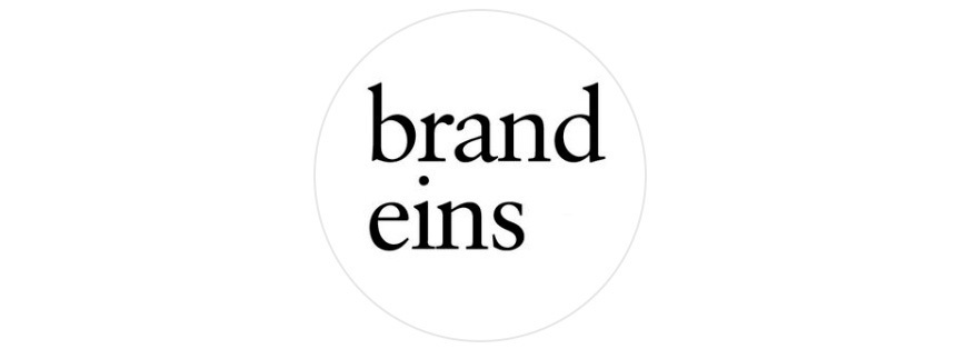 Das Bild zeigt einen weißen Kreis auf schwarzem Hintergrund. Im Kreis steht in schwarzer Schrift der Text "brand eins".