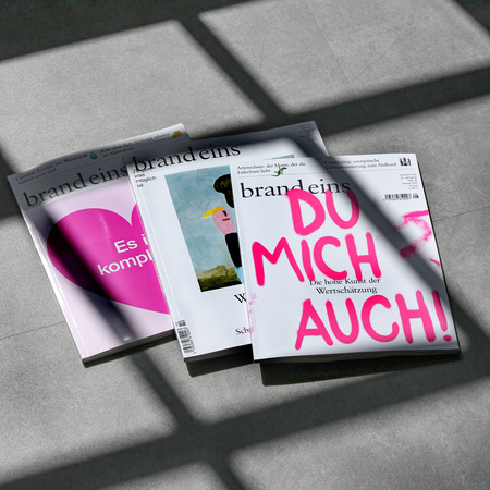 Mehrere Zeitschriften liegen übereinander auf einem dunklen Untergrund. Im Vordergrund ist eine Zeitschrift mit dem Titel "brand eins" und dem Aufdruck "DO MICH AUCH!" in großen, auffälligen Buchstaben zu sehen. Die Zeitschrift wirkt modern und ansprechend gestaltet. Im Hintergrund sind weitere Zeitschriften der gleichen Reihe erkennbar, die verschiedene Themen abdecken. Das Bild vermittelt einen Eindruck von Information, Wissen und Lifestyle.