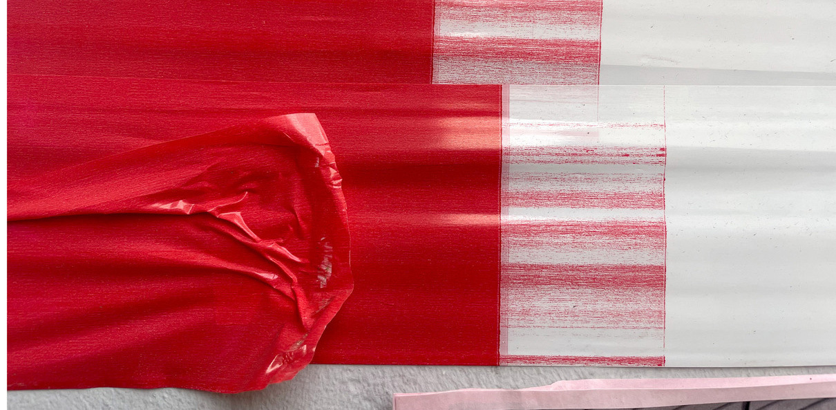 Abstrakte Grafik in Rot und Weiß. Ein rotes Stoffelement überlagert weiße, vertikal gestrichene Flächen. Die Komposition wirkt dynamisch und unregelmäßig.