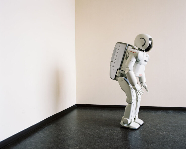 Ein weißer, humanoider Roboter steht in einem hellen Raum vor einer weißen Wand. Der Roboter scheint in einer Art nachdenklicher Pose zu stehen, den Kopf leicht gesenkt. Er ist von der Marke Honda.