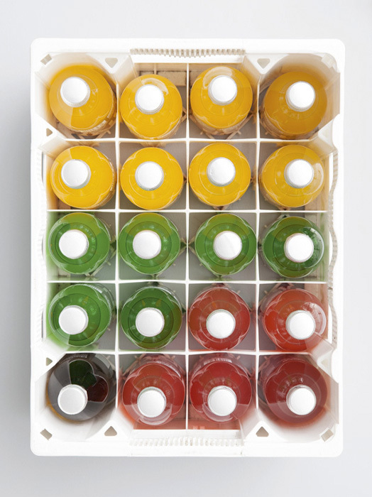 Ein weißer Kasten mit 24 kleinen Flaschen, angeordnet in einem Raster von 6 Reihen à 4 Flaschen. Die Flaschen sind in drei Farben unterteilt: Gelb, Grün und Rot. Die Flaschen sind vermutlich mit Flüssigkeit gefüllt.