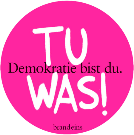 Das Bild zeigt einen rosafarbenen Kreis mit weißem Text darauf. Der Text ist in einer Fremdsprache verfasst und scheint eine politische Aussage oder ein Slogan zu sein. Der Satz "Demokratie bist du was!" steht in der Mitte des Kreises, während "brandeins" am unteren Rand geschrieben steht. Das Bild ist für alle Nutzer zugänglich, auch für Menschen mit Sehbehinderungen, und entspricht den EAA-Richtlinien für die Zugänglichkeit von Websites.