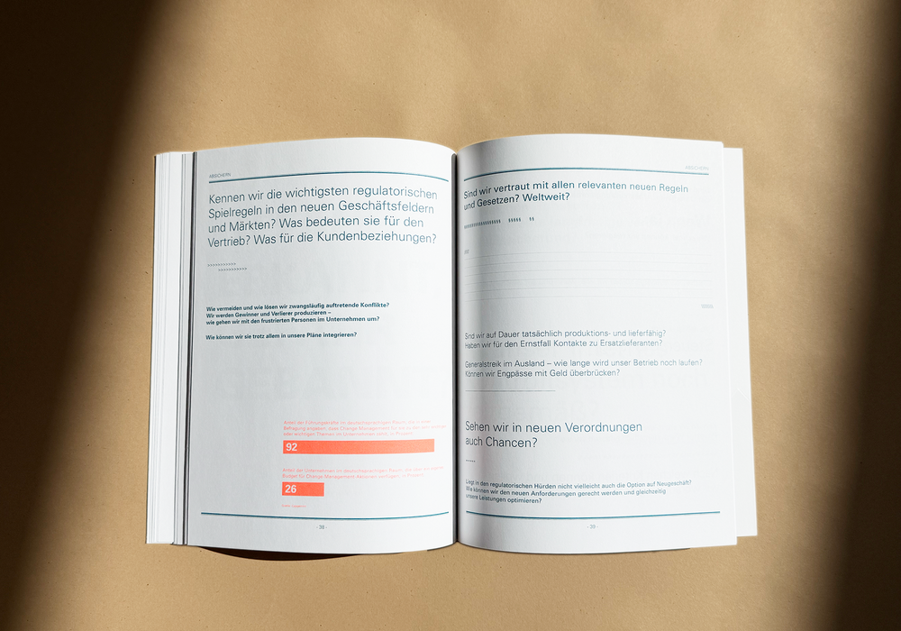 Das Bild zeigt ein aufgeschlagenes Buch mit deutschem Text auf beiden Seiten, das auf einer Oberfläche mit einem warmen, bräunlichen Ton liegt. Das Buch scheint ein technisches oder akademisches Dokument zu sein, möglicherweise im Zusammenhang mit Vorschriften oder Richtlinien. Der Text ist in deutscher Sprache, und auf der linken Seite befinden sich zwei orange-schwarze Indikatoren oder Zahlen, die möglicherweise auf einen Abschnitt oder eine Kapitelnummer hinweisen. Das Buch ist gut beleuchtet, und der Hintergrund ist unscharf, was die Aufmerksamkeit auf das Buch und seinen Inhalt lenkt.