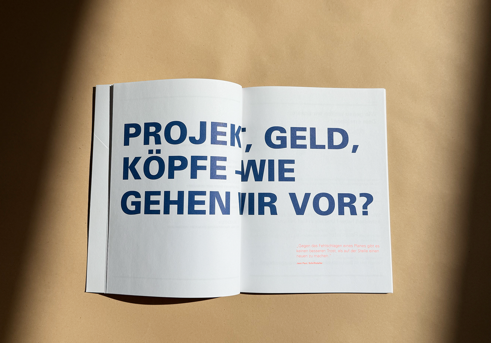 Das Bild zeigt eine aufgeschlagene Zeitschrift oder ein Buch mit einem großen Textabschnitt in blauen und weißen Farben. Der Text scheint auf Deutsch zu sein und ist in der Mitte der Seite positioniert. Der Hintergrund des Bildes ist beigefarben, und in der rechten unteren Ecke der Seite befindet sich ein kleiner Textabschnitt. Das Layout und die Gestaltung der Zeitschrift oder des Buches lassen darauf schließen, dass es sich um eine gedruckte Publikation handelt, die aufgrund ihrer Übereinstimmung mit den Richtlinien der EAA (European Association of Advertising Agencies) einem breiteren Publikum zugänglich ist.