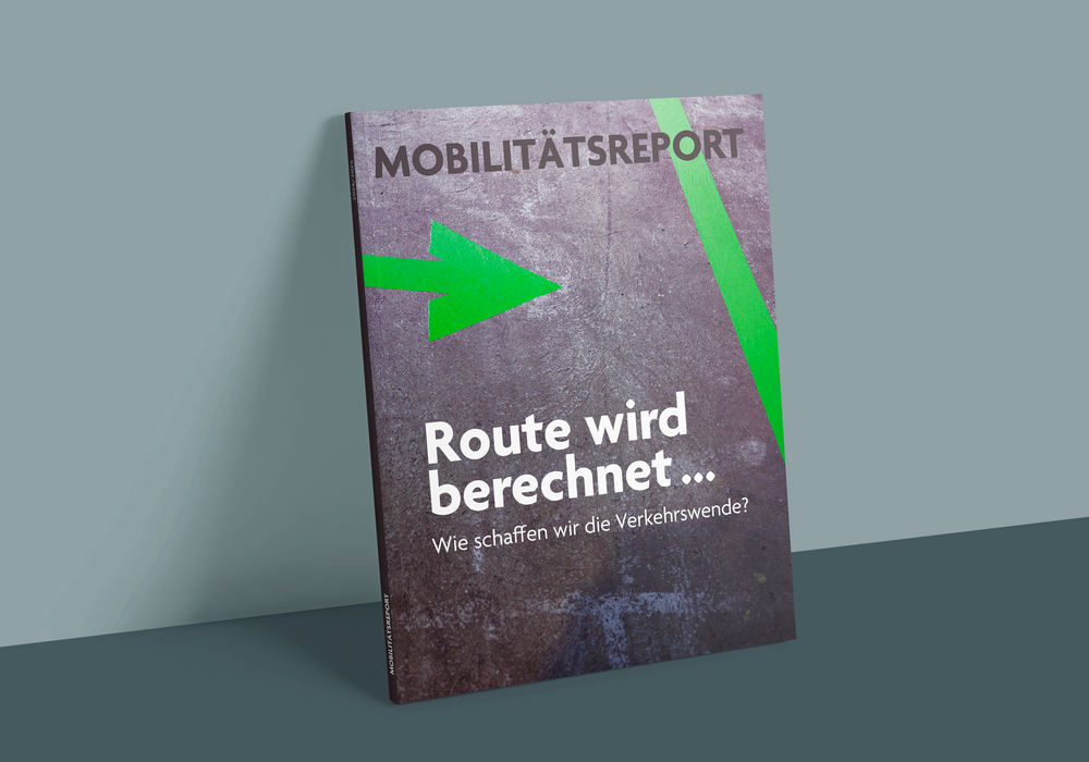 Das Bild zeigt ein Zeitschriftencover mit dunklem Hintergrund und einem grünen Pfeil, der nach rechts zeigt. Oben auf dem Cover steht in schwarzer Schrift der Titel "MOBILÄTSREPORT", gefolgt von dem Untertitel "Route wird berechnet..." in weißer Schrift. Unterhalb des Untertitels steht in kleinerer weißer Schrift "Wie schaffen wir die Verkehrswende? Der Umschlag enthält auch eine URL "www.mobilätsrep.de" am unteren Rand.