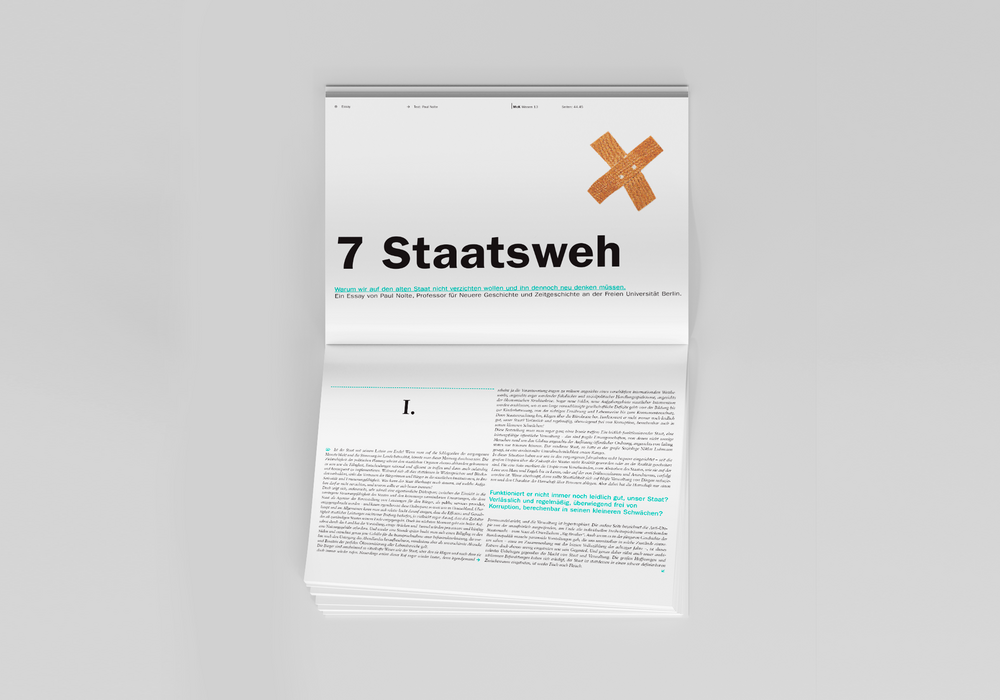 Das Bild zeigt ein aufgeschlagenes Buch mit weißem Einband und schwarzem Text, das auf einer weißen Fläche ausgelegt ist. Das Buch scheint eine Zeitschrift oder Publikation zu sein, mit einem auffälligen orangefarbenen Kreuzsymbol auf dem Einband. Der Text auf dem Einband ist auf Deutsch, und das Buch trägt den Titel "7 Staatsweh" auf Englisch. Das Layout und die Gestaltung des Buches lassen darauf schließen, dass es sich um eine gedruckte Publikation handelt, die möglicherweise zum Lesen oder Nachschlagen gedacht ist.