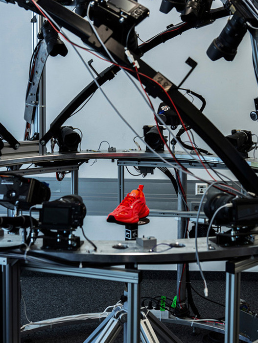 Das Bild zeigt eine technische Einrichtung mit verschiedenen elektronischen Geräten und Ausrüstungen, darunter Kameras, Drähte und ein rotes Objekt auf einem Metallständer. Die Einrichtung scheint sich in einem Raum mit grauem Boden und weißen Wänden zu befinden, was auf eine professionelle oder industrielle Umgebung hindeutet. Das Bild wird als technisches Bild beschrieben, was darauf hindeutet, dass es mit einem bestimmten Projekt oder einer bestimmten Aufgabe zusammenhängt, möglicherweise mit Fotografie oder Elektronik.