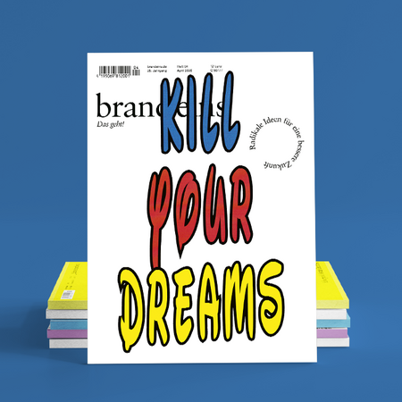 Das Bild zeigt ein lebhaftes Magazincover mit auffälligem, farbenfrohem Text, auf dem „Kill Your Dreams“ zu lesen ist. Das Cover ist vor einem blauen Hintergrund zu sehen, und im Vordergrund sind Stapel von Büchern zu erkennen. Der Text auf dem Cover scheint auf Deutsch zu sein, und in der oberen linken Ecke ist ein Barcode zu sehen. Das Layout und das Design des Magazincovers lassen darauf schließen, dass es sich um eine kreative und optisch ansprechende Publikation handelt.