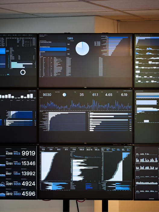 Das Bild zeigt eine Reihe von Computermonitoren, die in einem rasterartigen Muster angeordnet sind und jeweils verschiedene Grafiken, Diagramme und Datenvisualisierungen anzeigen. Die Monitore sind so angeordnet, dass sich die angezeigten Informationen leicht vergleichen und analysieren lassen. Das Bild ist in Schwarz-Weiß gehalten, was einer typischen Computerbildschirmdarstellung entspricht. Die Anordnung der Monitore lässt auf ein professionelles oder technisches Umfeld schließen, das möglicherweise für Datenanalyse, Überwachung oder Forschungszwecke genutzt wird.