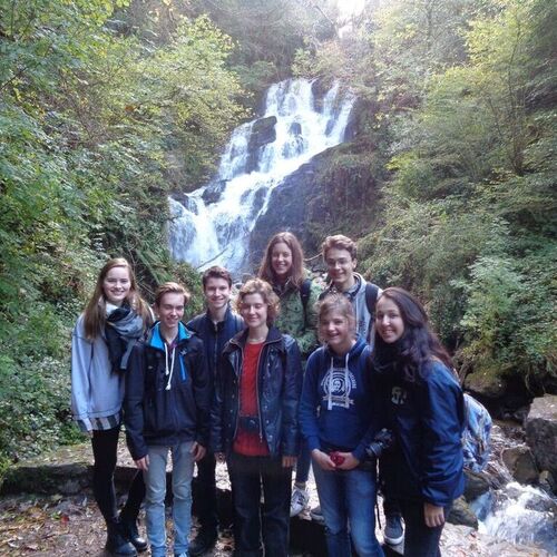 Austauschschüler mit Freunden vor Wasserfall in Irland